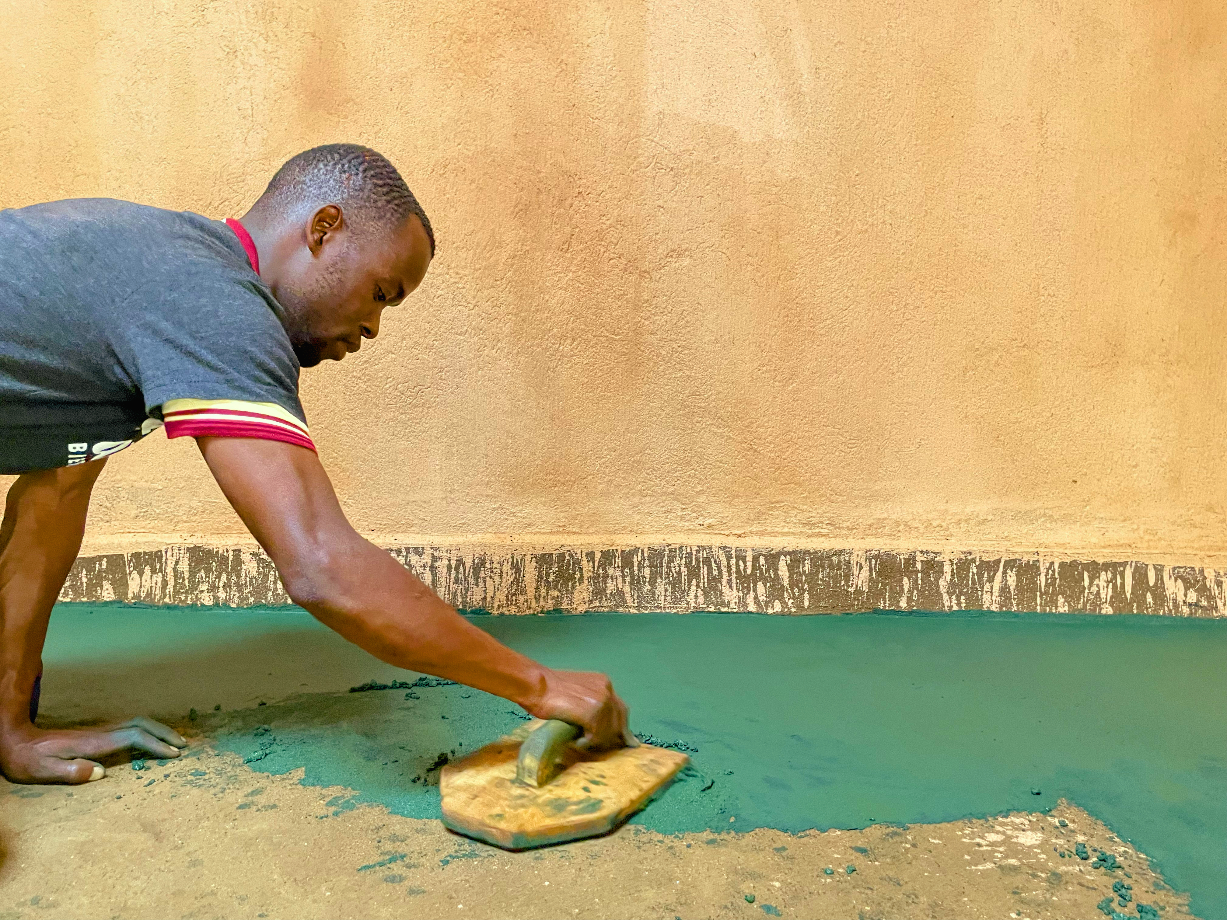 A trained Nyumba Nzuri artisan with a family in their finished home