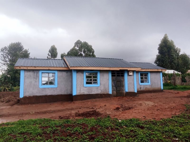 Completed earthen home with a sky-blue trim finish and dark corrugated roof