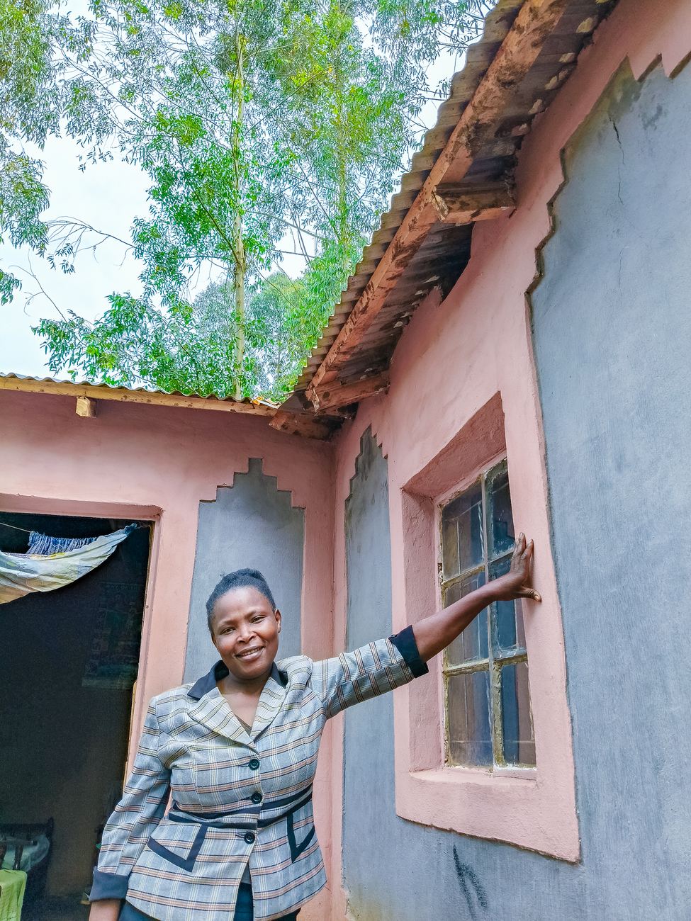 A homeowner smiling beside the window of her newly finished earthen home