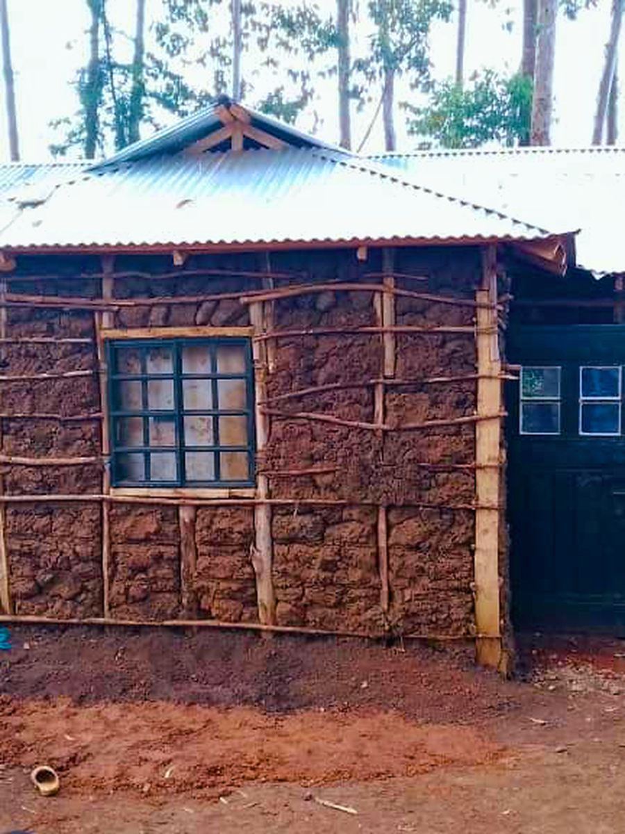 New earthen home under construction with timber frame and iron roof