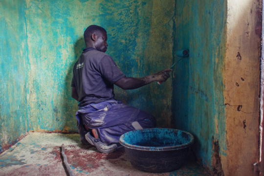 Artisan hands applying earthen plaster finish with a wooden trowel